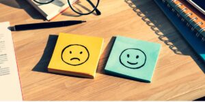 a smiling and frowning post it note on desk