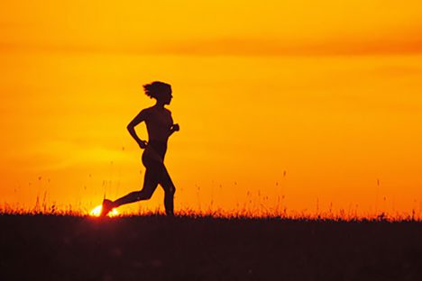 Silhouette of woman jogging at sunrise or sunset